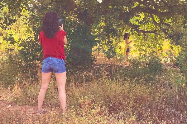 Adulta a fotografar uma menina entre árvores, imagem da criança interior, um dos temas das constelações familiares