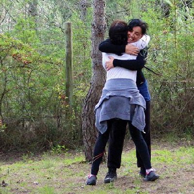 Abraço entre duas mulheres num bosque, o reencontro que uma sessão de constelação familiar pode trazer